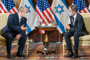 Prime Minister Bennett and Secretary Blinken sit in chairs and are speaking to each other, with U.S. and Israeli flags in the background.