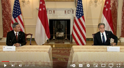 Secretary Blinken and Singaporean Foreign Minister Balakrishnan sit at desks with their country flags in the background.