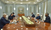 Deputy Secretary Sherman, Uzbekistan President Mirziyoyev, and other government officials sit around a large, wooden conference table .