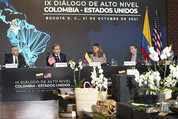 Secretary Blinken and other officials sit at a meeting table with the flags of the USA and Colombia in the background. 