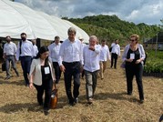 Mexican President Lopez Obrador points ahead as he walks with Special Envoy Kerry and others outdoors.