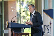 Secretary Blinken stands at a podium at the Foreign Service Institute, delivering his remarks into a microphone. 