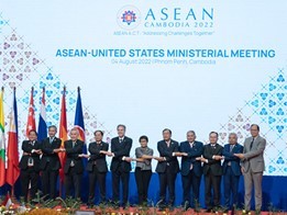 Eleven people, including Secretary Blinken, stand holding hands in front of a large sign that reads “ASEAN-United States Ministerial Meeting”. 