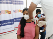 Woman in a pink shirt receiving a vaccine on her arm. 