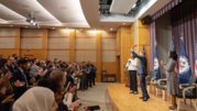 Secretary of State Antony Blinken waves to team members assembled in an auditorium.