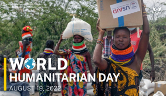 Women wearing brightly-colored necklaces transport on their heads sacks and boxes of aid donated by USAID.