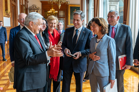 Secretary Blinken, President Obrador, Secretary Raimondo and others smile during a conversation in a hallway