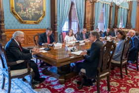 Secretary Blinken, President Obrador, and other officials sit together at a long table in an ornate conference room