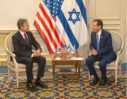 Secretary Blinken sits across from President Herzog. Flags of the United States and Israel are placed behind them. 