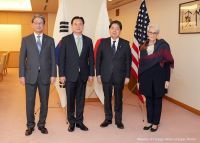 Deputy Secretary Sherman stands with Japanese and ROK officials in a conference room with the flags of their countries behind them.