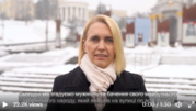 Ambassador Brink, wearing a black coat and a beige scarf, speaks outside, with a snowy street scene behind her. 