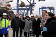 U.S. and Ukrainian officials, wearing coats and some with hardhats, stand together at Odesa Port. 