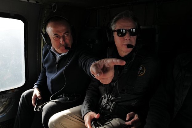 Foreign Minister Cavusoglu and Secretary Blinken, wearing headsets while sitting in a helicopter, survey damage from the earthquakes. 