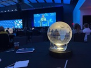 Mashal Hussain, COO of the World Food Prize, speaks on stage. Lighted globes are visible on audience tables.