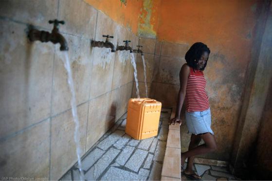 A young woman in Haiti collects drinking water.
