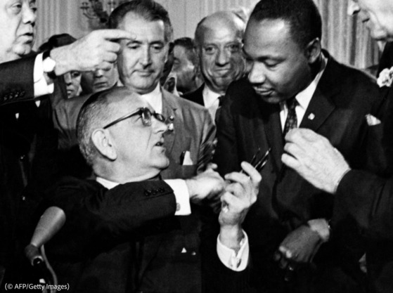 President Lyndon B. Johnson hands a pen to Martin Luther King Jr. after signing the Civil Rights Act on July 2, 1964.