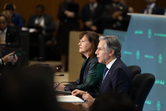 Secretary Blinken sitting in a room next to a woman, speaks at the D-ISIS Ministerial at the Department of State in Washington.