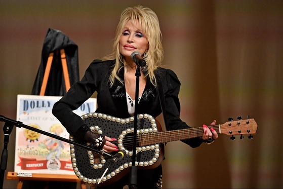 Dolly Parton playing a guitar to celebrate the expansion of her Imagination Library in Kentucky.