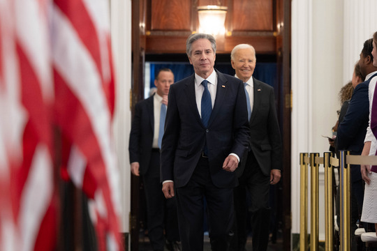 Secretary Blinken walks in front of President Biden as he prepares to give remarks.