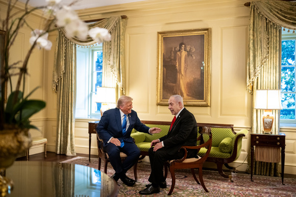 President Trump gesturing toward Israeli Prime Minister Netanyahu while they are seated in the White House.