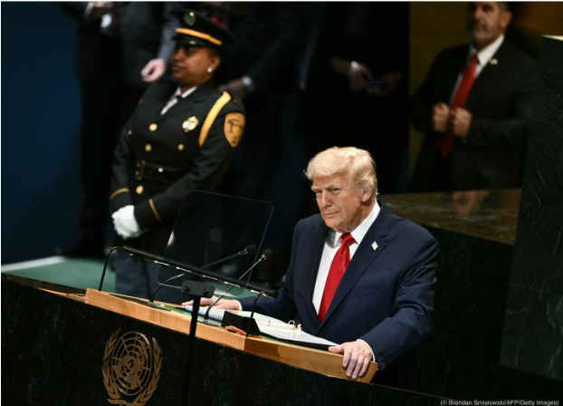 President Trump stands -behind a lectern with the UN symbol on it.