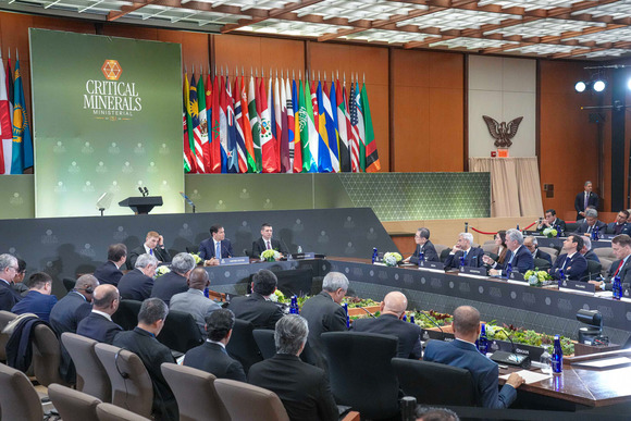 Secretary Rubio and a group of officials sit at a large rectangular table in front of microphones.