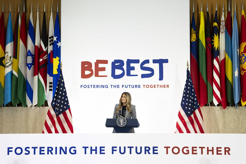 First Lady Melania Trump speaks from behind a lectern with the State Department seal.