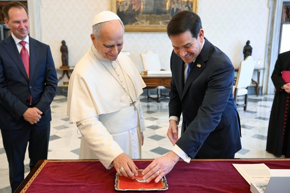 Secretary Rubio and Pope Leo XIV inspect a crystal football in a reception room, flanked by two deputies in the background.