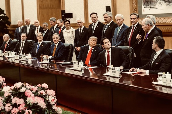 President Trump and Secretary Rubio look to the side while sitting at a table with other officials.