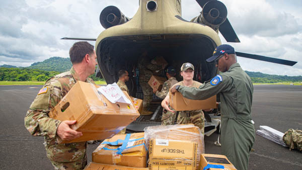Six service members load boxes of supplies onto a helicopter.