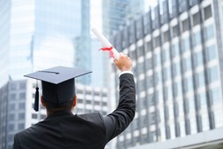 man holding diploma and wearing graduation cap