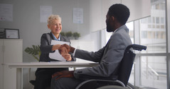 job candidate in wheelchair shaking hands with female employer