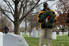 man laying wreath at gravesite