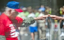 veteran touching vietnam memorial wall