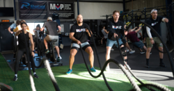 men and woman using battle ropes in a gym