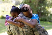 two children hugging their father who is wearing a military uniform