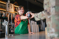 barista handing coffee to person in military uniform