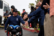 man in wheelchair shaking hands with welcoming volunteers