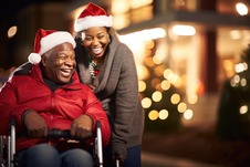 man in wheelchair and his daughter laughing and wearing santa hats