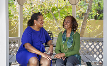 two women smiling and talking while sitting in a gazebo 