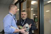 Two men having a discussion while looking at a piece of athletic equipment.