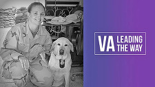 Female Veteran in uniform kneeling next to dog.