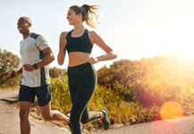 A woman and a man jogging and smiling.