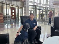 Woman sitting in a chair with a service dog next to her.