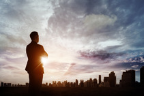 Man in a business suit looking out at city skyline.