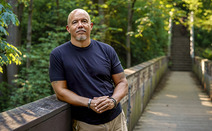 Man leaning against a bridge railing.