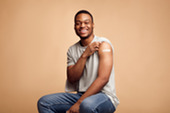 African American man with his sleeve rolled up showing band aid on arm from vaccine.