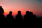 Silhouette of four people looking at the sunset.