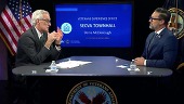 Two men seated at a table for a town hall.