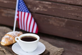 Cup of coffee next to a small American Flag.